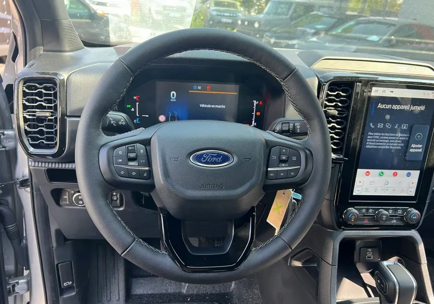 Vue intérieure centrée sur le volant du Ford Ranger 2025 gris iconic avec tableau de bord digital et écran tactile vertical.