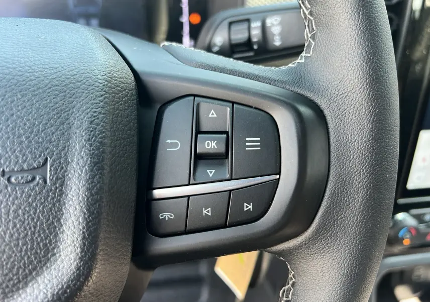 Gros plan sur les commandes au volant du Ford Ranger 2025, boutons noirs avec fonction appel et navigation.