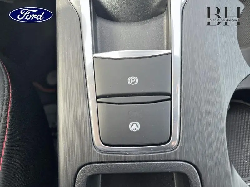 Gros plan sur la console centrale gris foncé du Ford Kuga 2026 avec boutons de frein à main électronique et maintien auto.