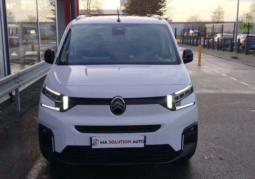 Vue de face du Citroën Berlingo blanc Kaolin avec phares LED allumés et calandre noire distinctive.