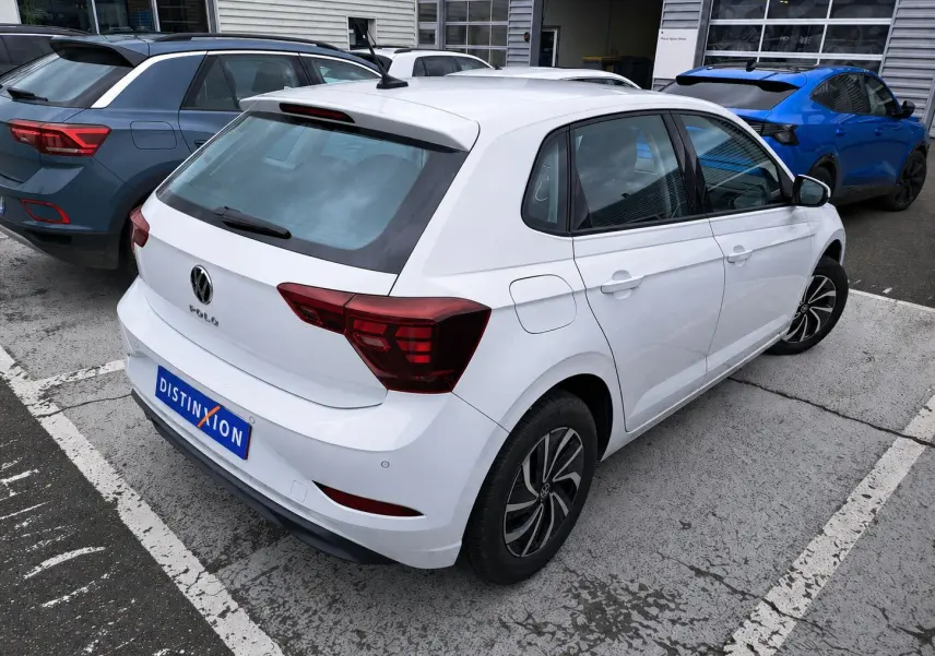 Vue 3/4 arrière droite d'une Volkswagen Polo blanche 2023 avec feux arrière LED et jantes alliage noires.