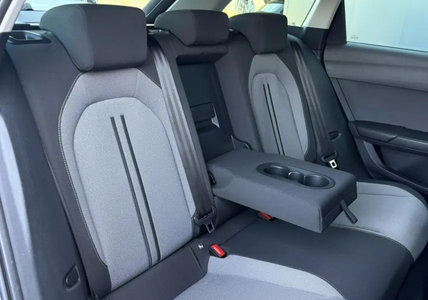 Vue intérieure des sièges arrière gris clair et noir du SEAT LEON ST avec accoudoir central et porte-gobelets déployé.