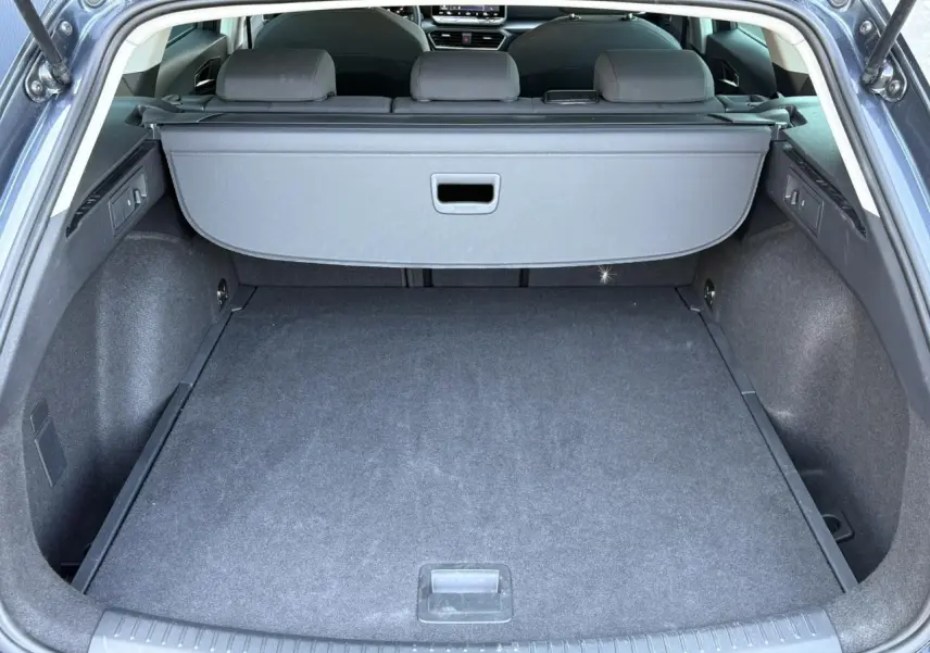 Coffre ouvert vu de l'arrière d'une SEAT LEON ST gris magnétique avec cache-bagages et sièges arrière rabattus.