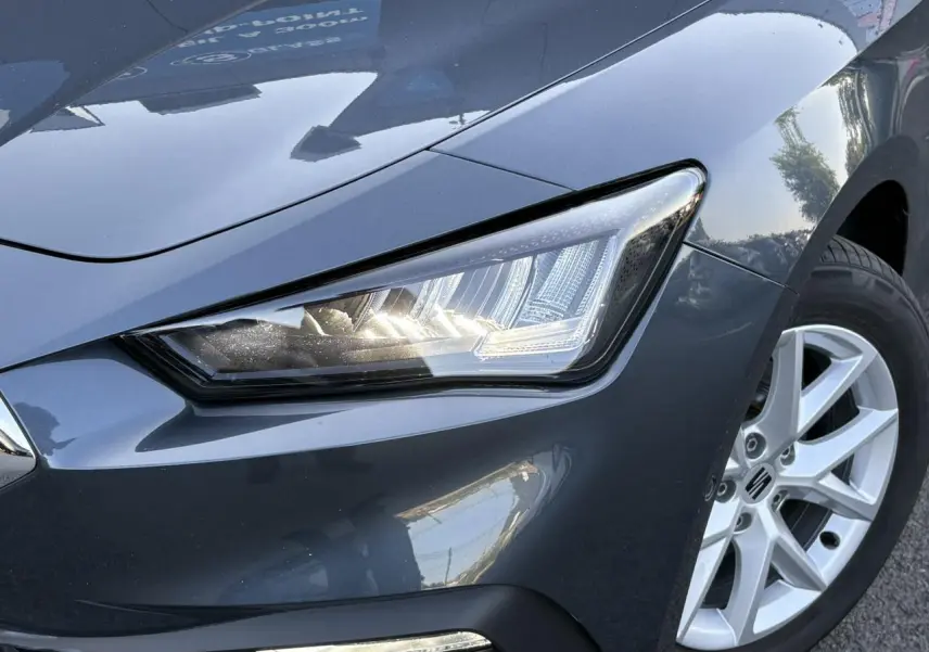 Gros plan sur l'avant droit gris magnétique du SEAT LEON ST 2025, mettant en valeur le phare LED et la jante alliage 16 pouces.