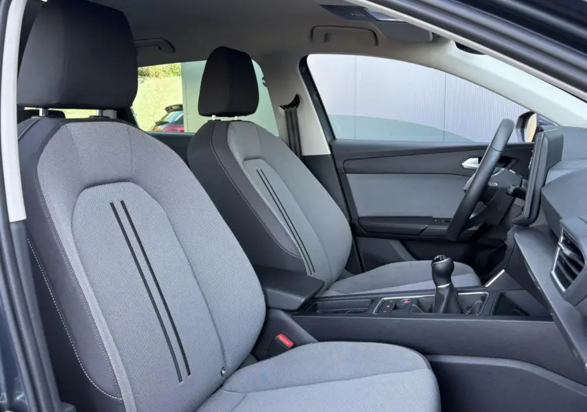 Vue intérieure côté droit du SEAT LEON ST 1.5 TSI 115 Style 2025, sièges textile gris clair avec console centrale noire.