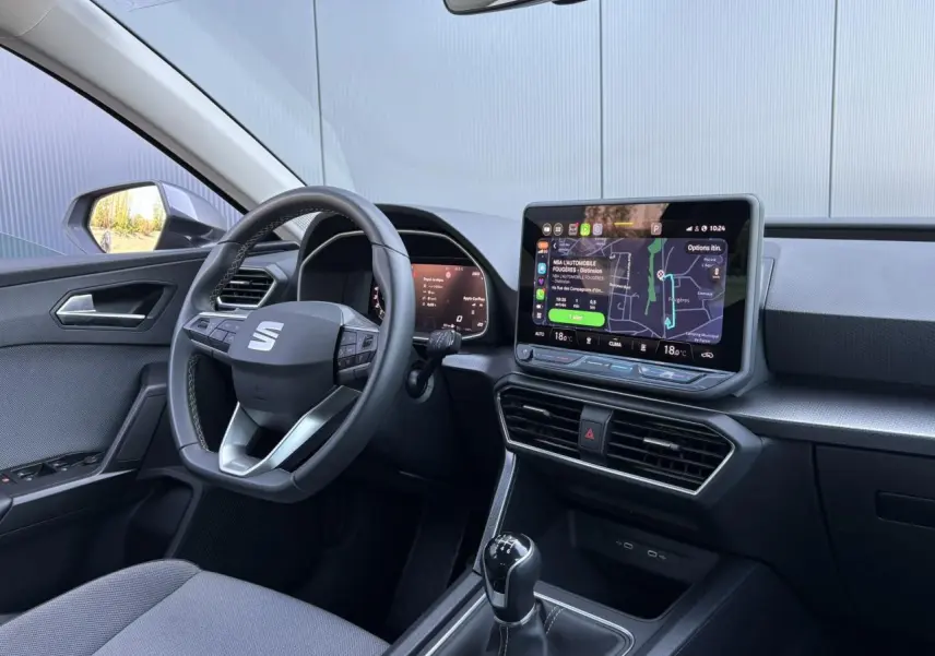 Vue intérieure côté conducteur du SEAT Leon ST 2025, avec volant cuir multifonction et écran tactile central lumineux.