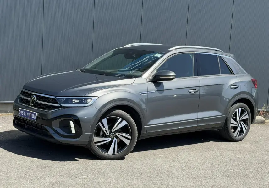 Volkswagen T-Roc gris Indium en 3/4 avant droit, avec jantes alliage 18" Nevada et logo R-Line sur calandre.