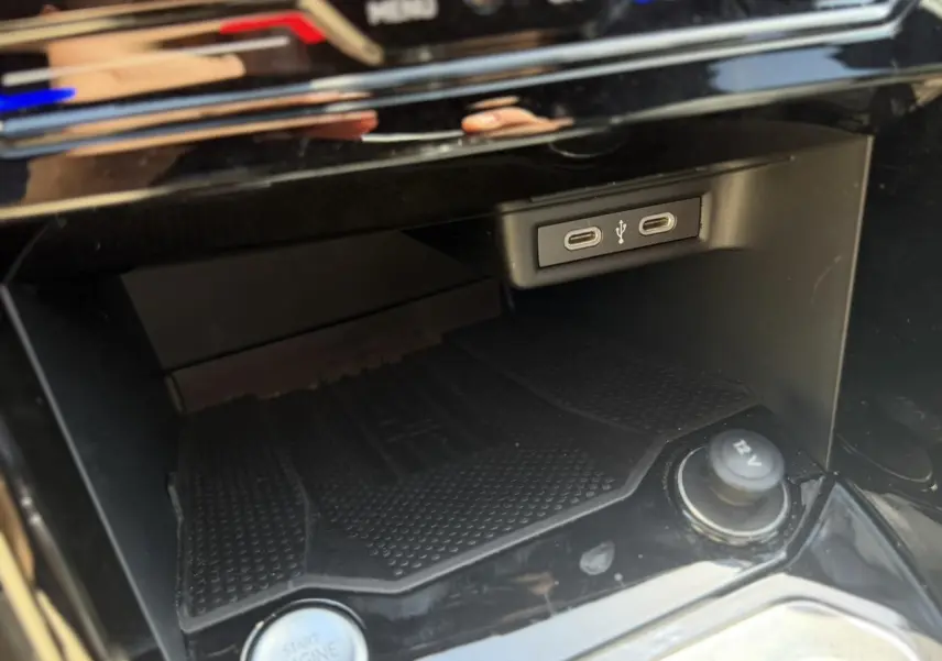 Gros plan sur la console centrale noire du Volkswagen T-Roc 2025, montrant ports USB-C, bouton start/stop et prise 12V.