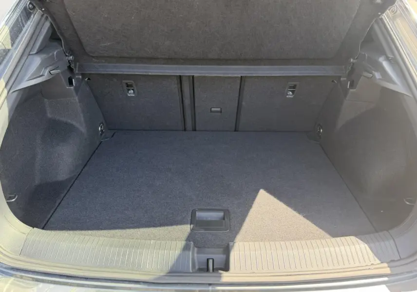Coffre ouvert vu de l'arrière d'un Volkswagen T-Roc gris Indium, espace de chargement propre et spacieux.