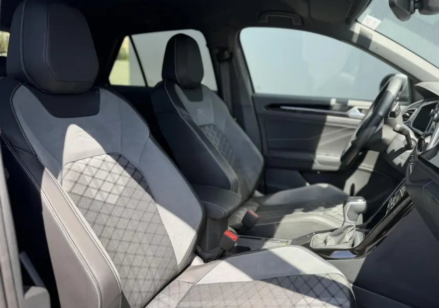 Vue intérieure côté gauche montrant les sièges avant gris avec surpiqûres et logo R-Line du Volkswagen T-Roc 2025.