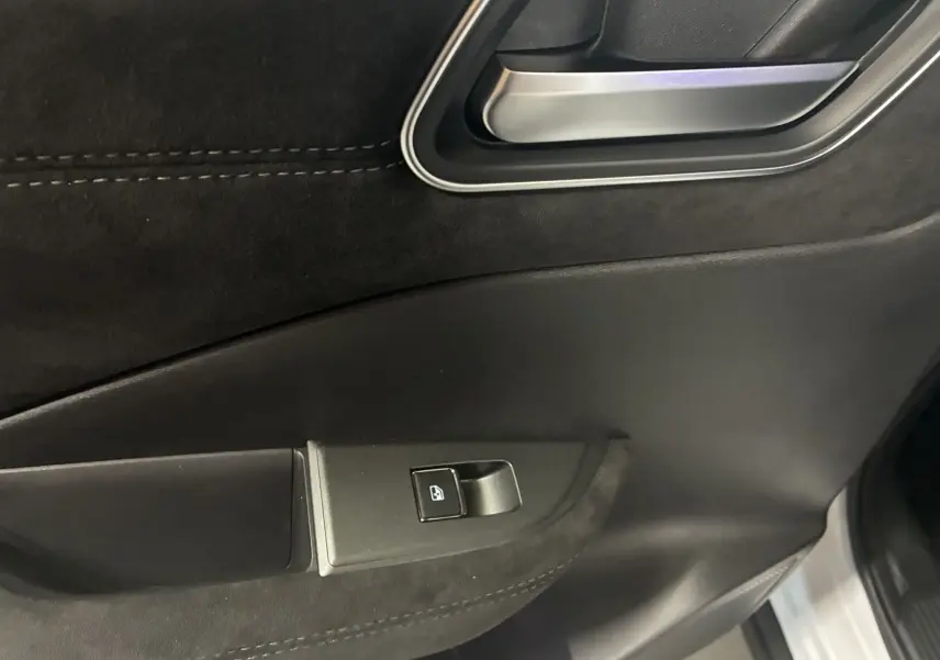 Gros plan sur la poignée intérieure et le bouton de lève-vitre côté conducteur du Nissan Qashqai blanc nacré 2025.