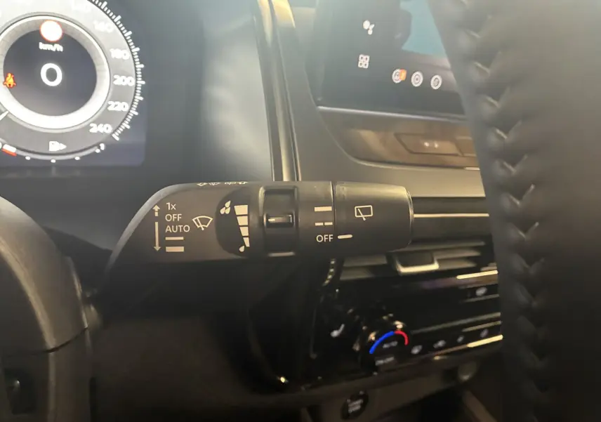 Gros plan sur la commande d’essuie-glace à gauche du volant dans l’habitacle noir du Nissan Qashqai blanc nacré 2025.