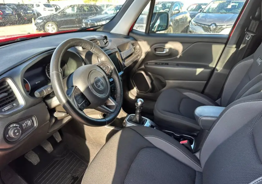 Intérieur du Jeep Renegade 2022, vue côté conducteur, volant cuir, sièges tissu gris et accoudoir central.