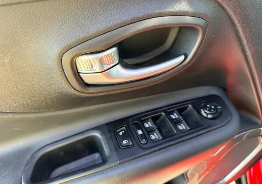 Poignée intérieure et commandes électriques de la porte côté conducteur d’un Jeep Renegade rouge 2022.