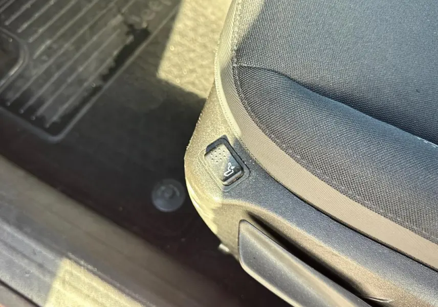 Gros plan sur le bouton de réglage lombaire du siège conducteur en tissu noir dans une Jeep Renegade 2022.