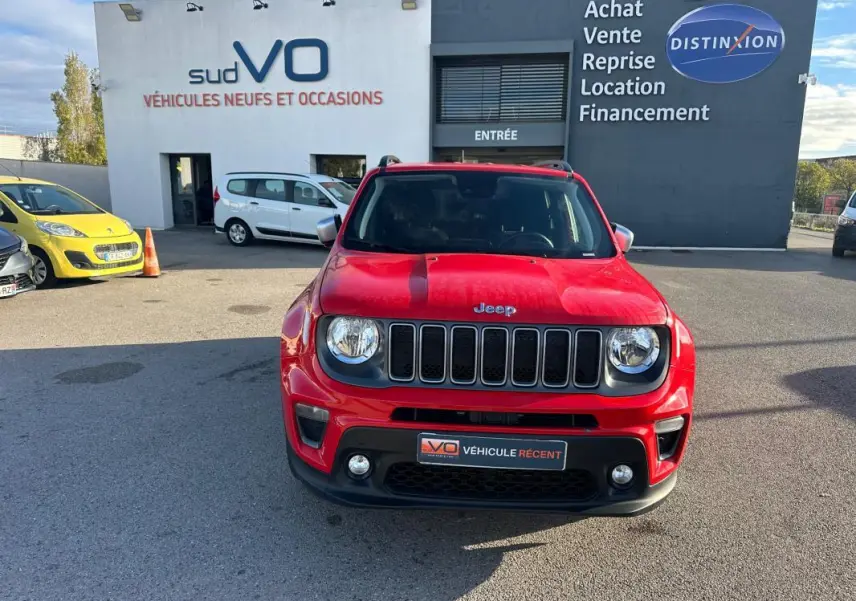 Vue de face d'un Jeep Renegade rouge 2022 avec calandre à sept fentes et phares ronds, stationné devant un concessionnaire.