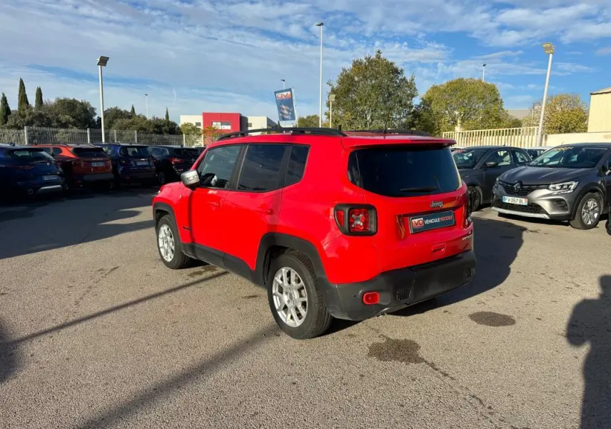 Jeep Renegade rouge vue 3/4 arrière droit avec barres de toit et jantes alliage 17 pouces sur parking.
