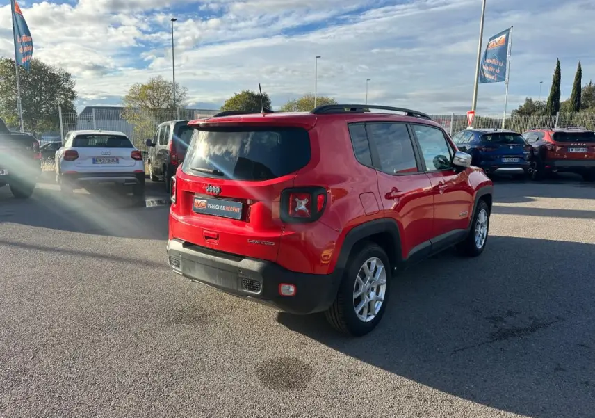 Jeep Renegade rouge vue 3/4 arrière droit, avec barres de toit et jantes alliage 17 pouces sur parking.