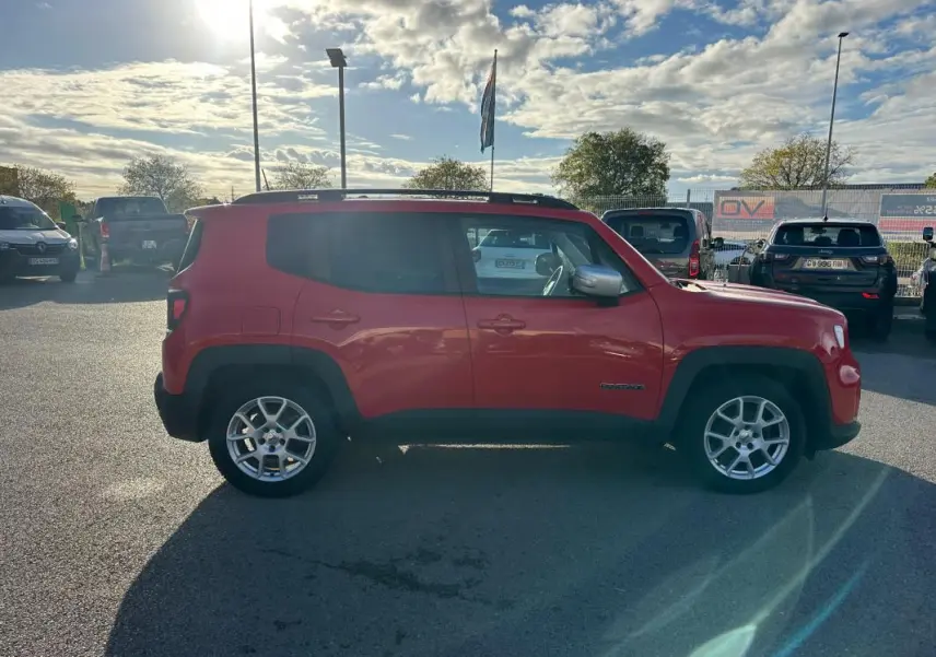 Profil côté gauche d'un Jeep Renegade rouge 2022 avec barres de toit et jantes alliage 17 pouces.