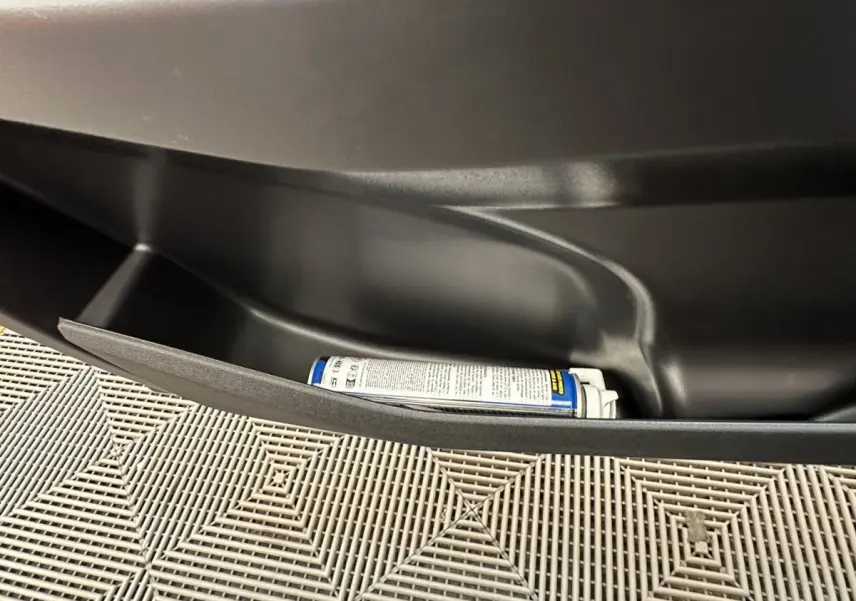 Rangement de porte intérieur noir avec un spray, sur une Aixam Ambition E City Pack blanc, vue côté conducteur.