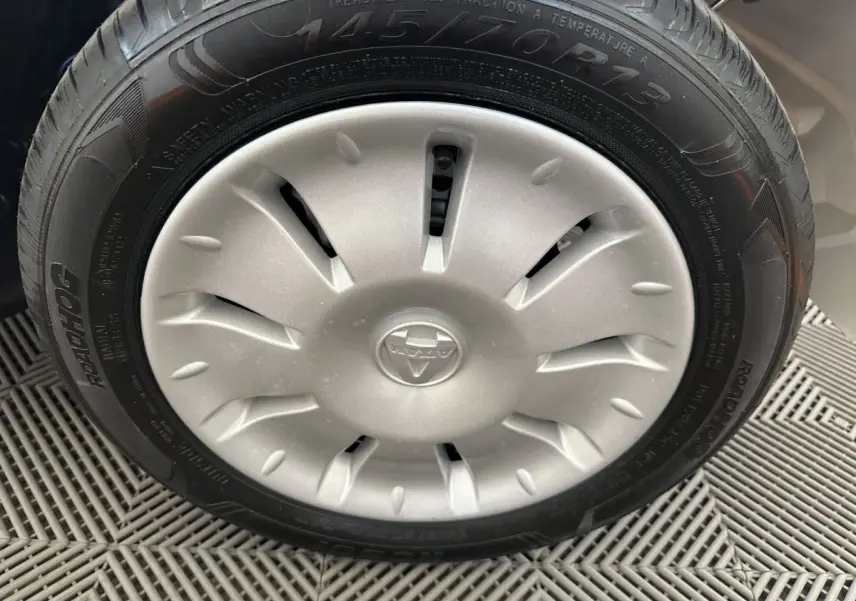 Gros plan sur la roue avant droite d'une Aixam Ambition E City Pack blanche, avec enjoliveur argenté et logo central.