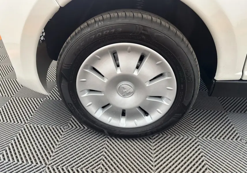 Gros plan sur la roue avant gauche blanche d'une Aixam Ambition E City Pack 2025 avec enjoliveur argenté.