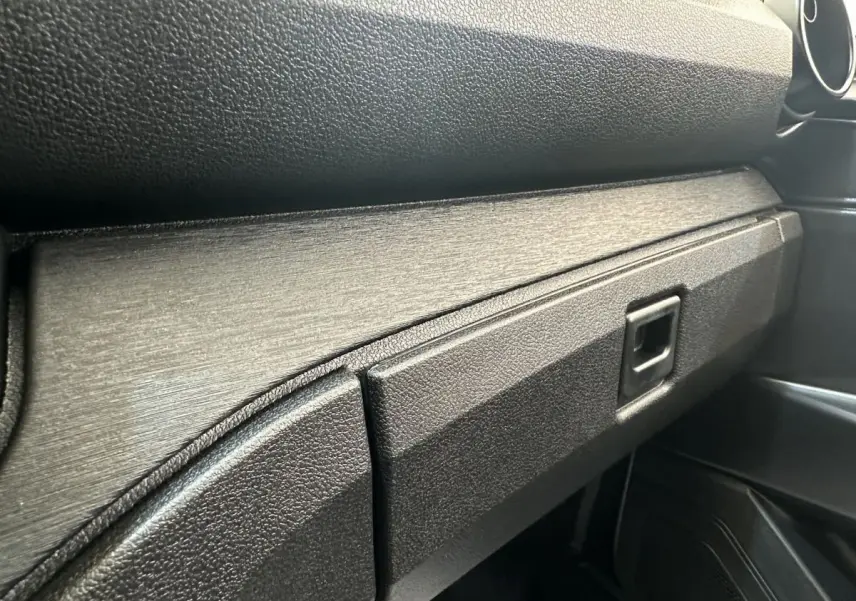 Gros plan sur la boîte à gants et la planche de bord noire texturée de l'AIXAM AMBITION E CITY PACK 2025.