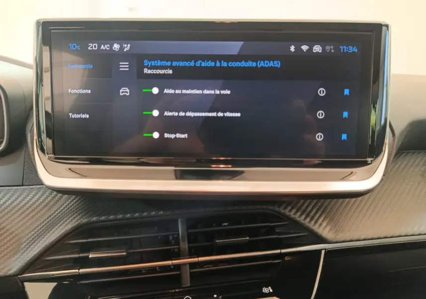 Vue rapprochée de l’écran tactile central affichant les aides à la conduite dans l’habitacle gris foncé du Peugeot 208 2025.
