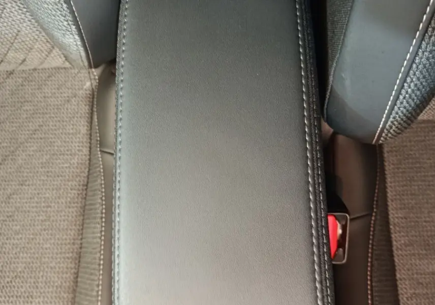 Vue plongeante sur l'accoudoir central en cuir noir entre les sièges tissu gris foncé d'une Peugeot 208 2025.
