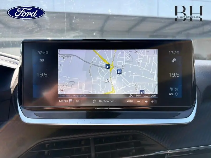 Écran tactile central du tableau de bord avec navigation GPS affichée, intérieur noir moderne.