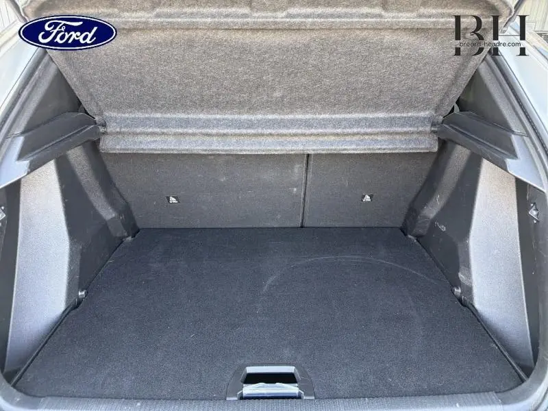 Coffre ouvert vu de l'arrière d'un Peugeot 2008 blanc nacré, montrant l'espace de chargement vide et la tablette cache-bagages.