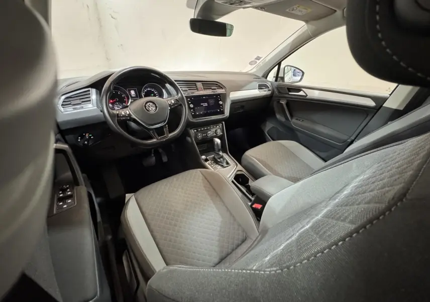 Vue intérieure côté conducteur du Volkswagen Tiguan 2020, montrant le volant cuir, tableau de bord numérique et sièges gris.
