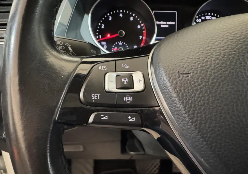 Gros plan sur les commandes du volant cuir noir du Volkswagen Tiguan 2020, avec tableau de bord numérique en arrière-plan.