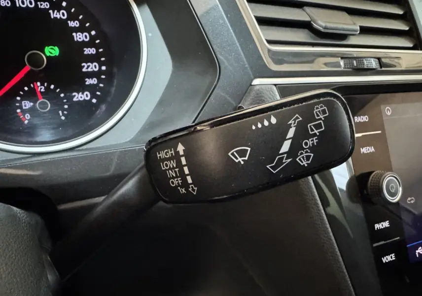 Gros plan sur la commande des essuie-glaces du Volkswagen Tiguan 2020, tableau de bord noir et écran tactile visible.