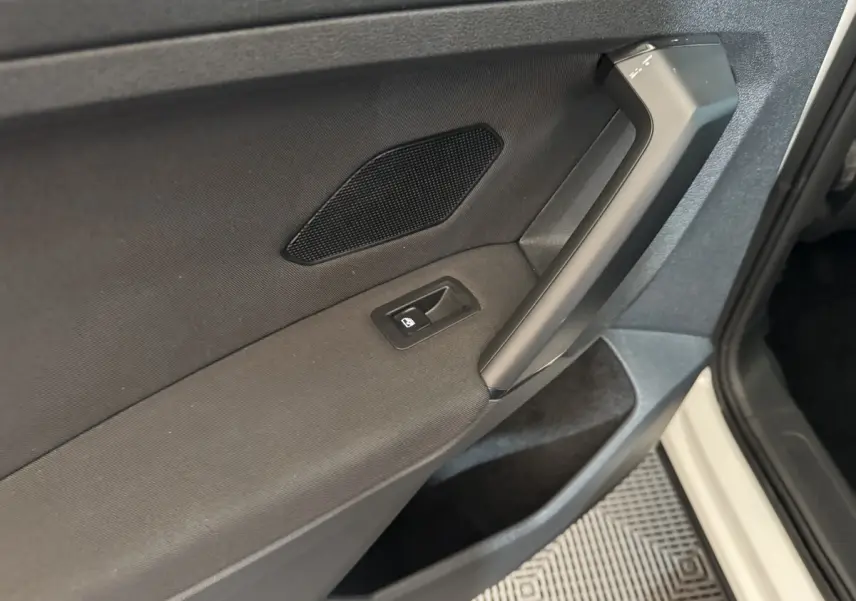 Gros plan sur la porte avant gauche noire du Volkswagen Tiguan blanc, avec poignée et bouton de vitre électrique.