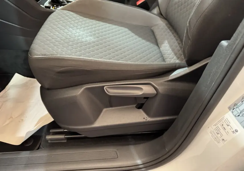 Gros plan sur le siège avant droit gris à motifs du Volkswagen Tiguan blanc, avec réglage manuel visible.