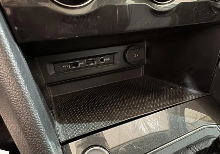 Gros plan sur la console centrale noire du Volkswagen Tiguan 2020 montrant ports USB et prise 12V.