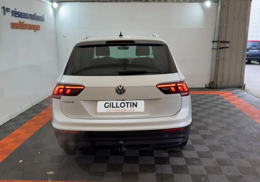 Vue arrière d'un Volkswagen Tiguan blanc 2020 avec feux allumés et attelage dans un garage.