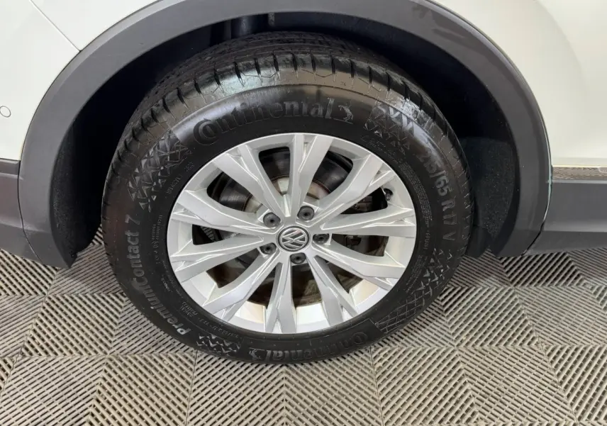 Gros plan sur la roue avant droite d'un Volkswagen Tiguan blanc, mettant en valeur la jante alliage et le pneu Continental.