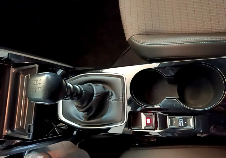 Gros plan sur la console centrale noire de la Peugeot 208 jaune, avec levier de vitesse manuel et porte-gobelets.