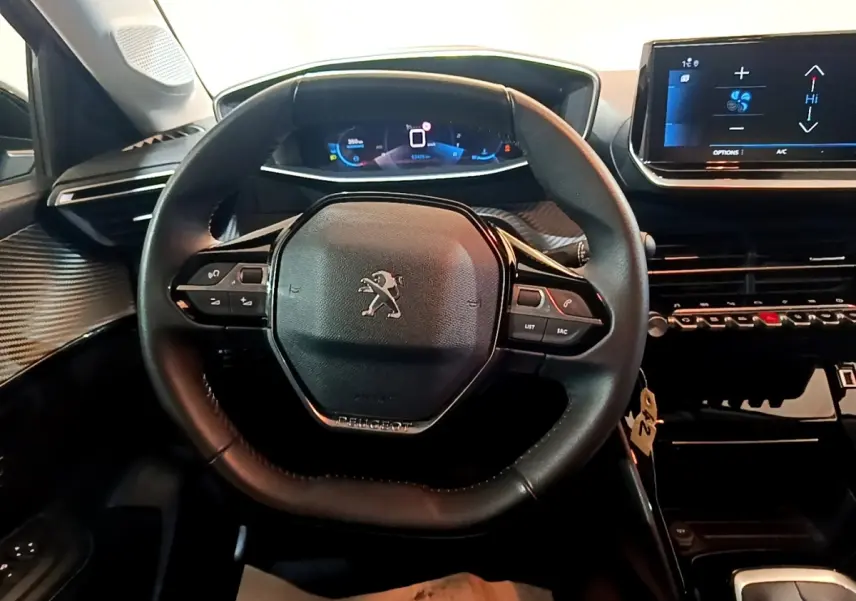 Vue intérieure centrée sur le volant cuir multifonctions de la Peugeot 208, avec tableau de bord digital et écran tactile.