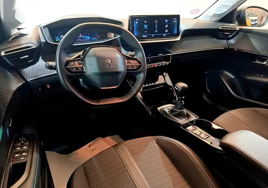 Vue intérieure avant droite du Peugeot 208 PureTech 100 S&S Allure Pack 2023, volant cuir multifonctions et écran tactile central.