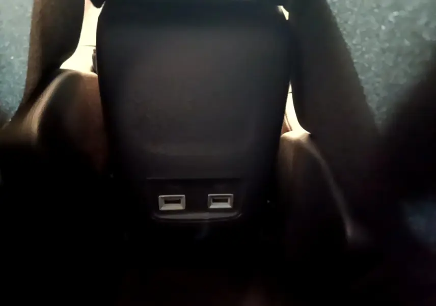 Gros plan sur les ports USB arrière noirs du siège central dans l’habitacle d’une Peugeot 208 jaune 2023.