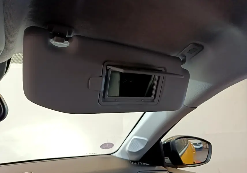 Vue intérieure côté conducteur du pare-soleil avec miroir ouvert, reflet du Peugeot 208 jaune dans le rétroviseur extérieur.