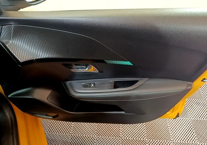 Vue intérieure de la porte avant gauche noire avec surpiqûres bleues sur Peugeot 208 jaune 2023.