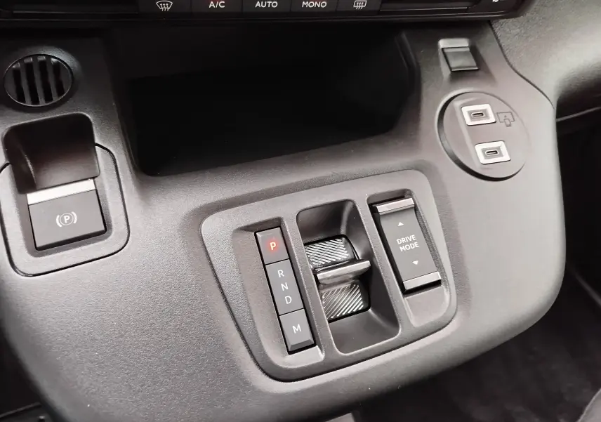 Vue rapprochée de la console centrale grise du Citroën Berlingo 2025, avec commandes de boîte auto et mode de conduite.