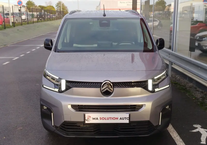 Vue avant d'un Citroën Berlingo 2025 gris acier avec phares LED allumés sur un parking extérieur.