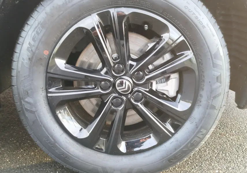 Gros plan sur la roue avant droite du Citroën Berlingo 2025 avec jante noire brillante et logo Citroën central.