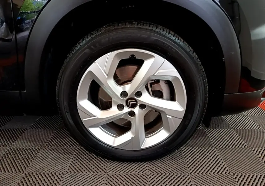 Gros plan sur la roue avant droite d’un Citroën C5 Aircross noir, avec jante alliage argentée à cinq branches.