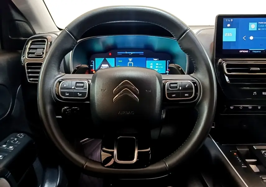 Vue intérieure centrée sur le volant cuir noir et le combiné numérique du tableau de bord du Citroën C5 Aircross hybride.